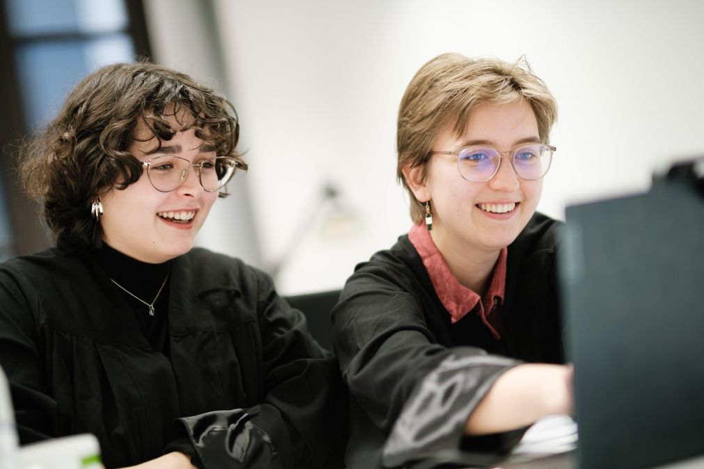 zur Vergrößerungsansicht des Bildes: zwei Frauen sitzen vor Computer und lachen 