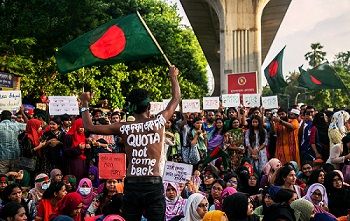 Protestierende, im Vordergrund schwenkt ein Mann die Flagge Bangladeshs