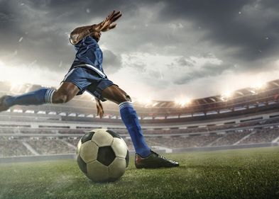 Zu sehen ist ein Fußballer mit dunkler Hautfarbe beim Elfmeterschuss.